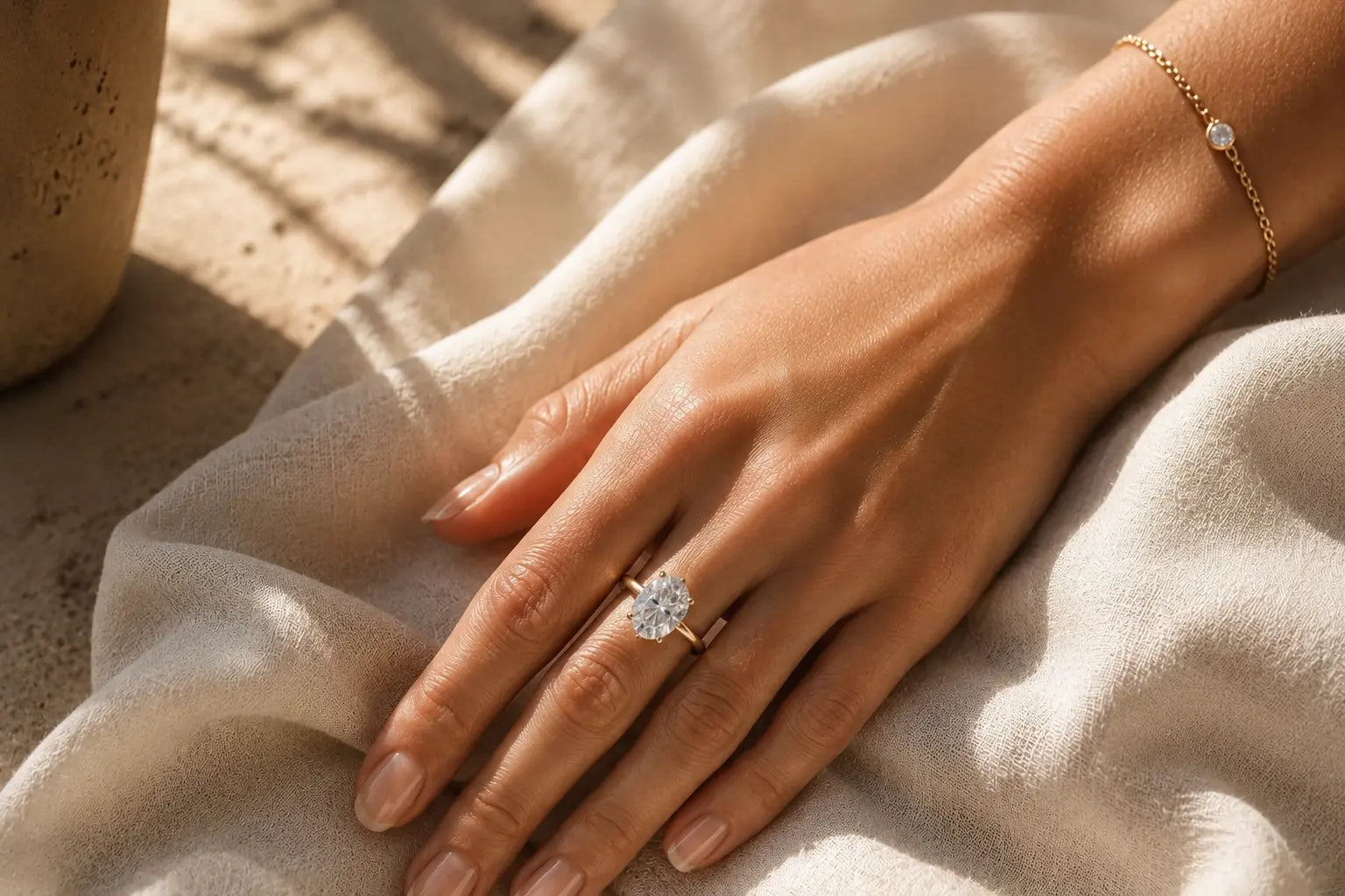 Woman's hand wearing an Aquae Jewels solitaire diamond ring and chain bracelet handcrafted in solid 18K gold, covered by the 5-Year Warranty