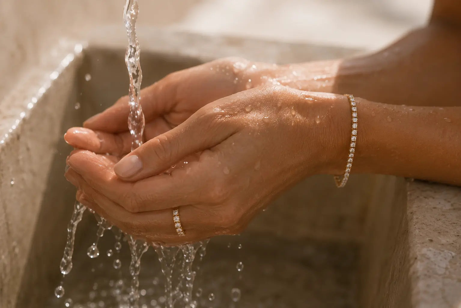 Hands rinsing under running water while wearing an Aquae Jewels diamond tennis bracelet and ring in water-resistant solid 18K gold